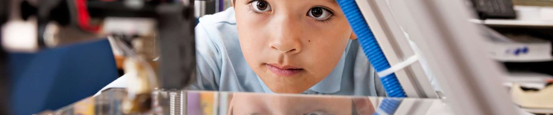 A boy watching a 3D printer