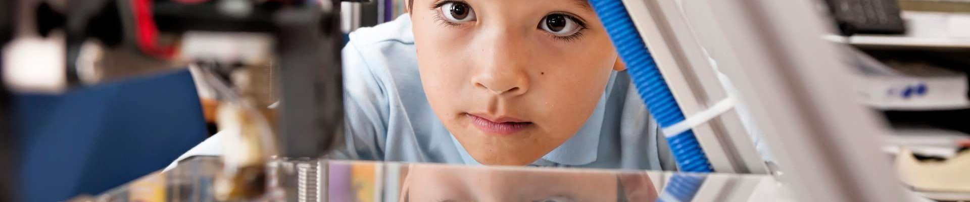 A boy watching a 3D printer